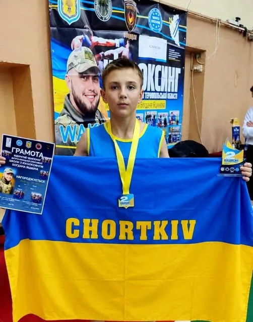 Хлопець з Чорткова тримає прапор, грамоту й медаль за друге місце