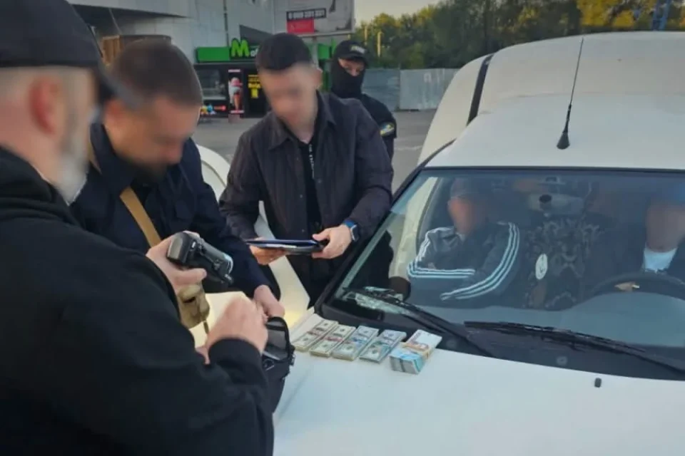 Правоохоронці біля білого авто з пачками грошей на капоті